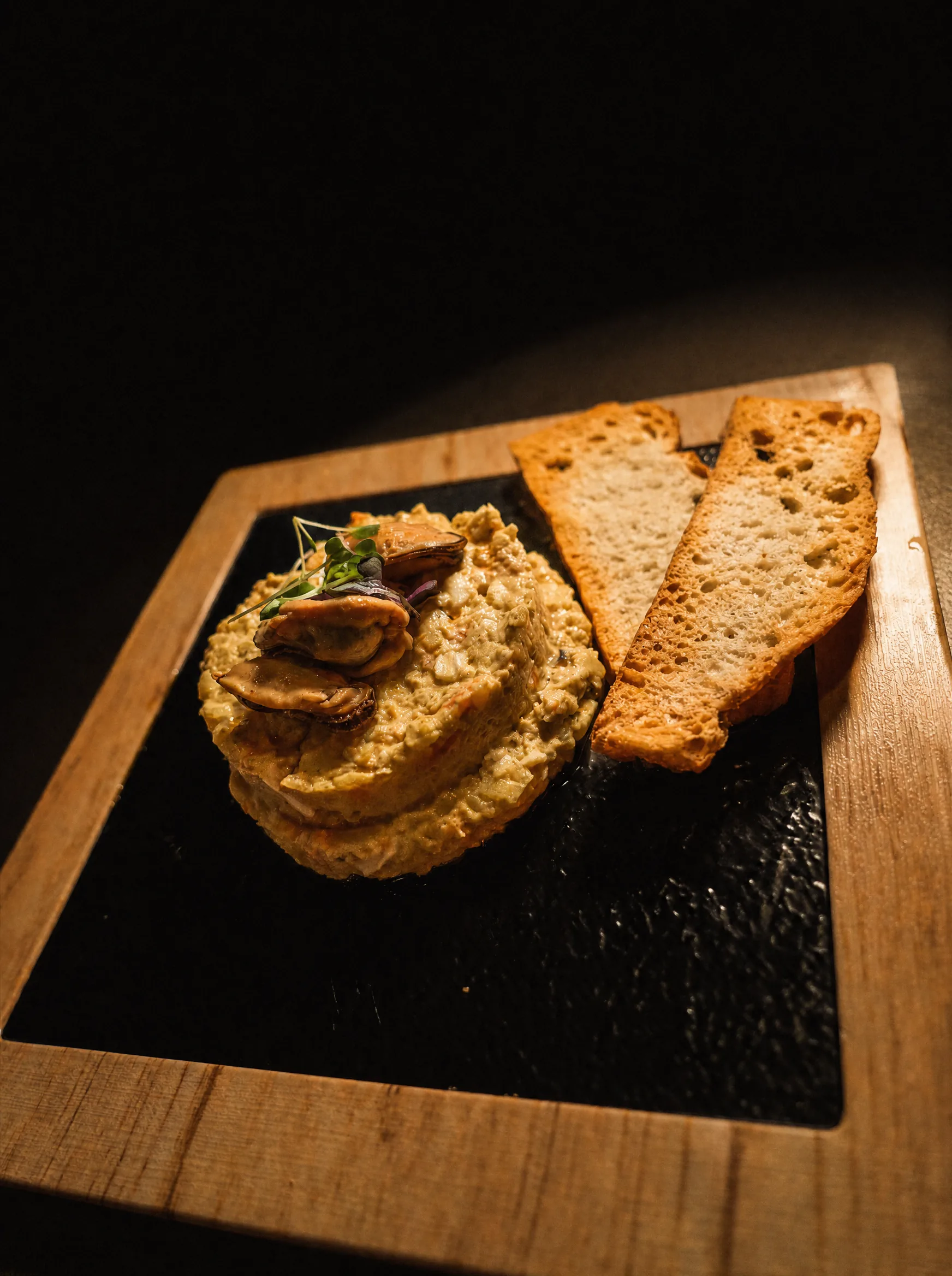 Crema untable con setas salteadas y tostas de pan en tabla